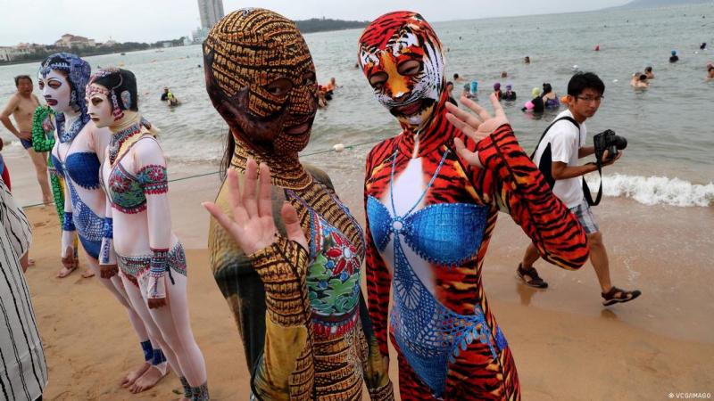 DW - Modelos con "facekinis" posan para una foto en una playa el 5 de agosto de 2019 en Qingdao, provincia china de Shandong.
