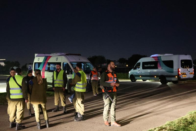 AFP - Las fuerzas de seguridad israelíes se encuentran cerca de vehículos que esperan transportar a dos rehenes ruso-israelíes tomados por militantes de Hamás.