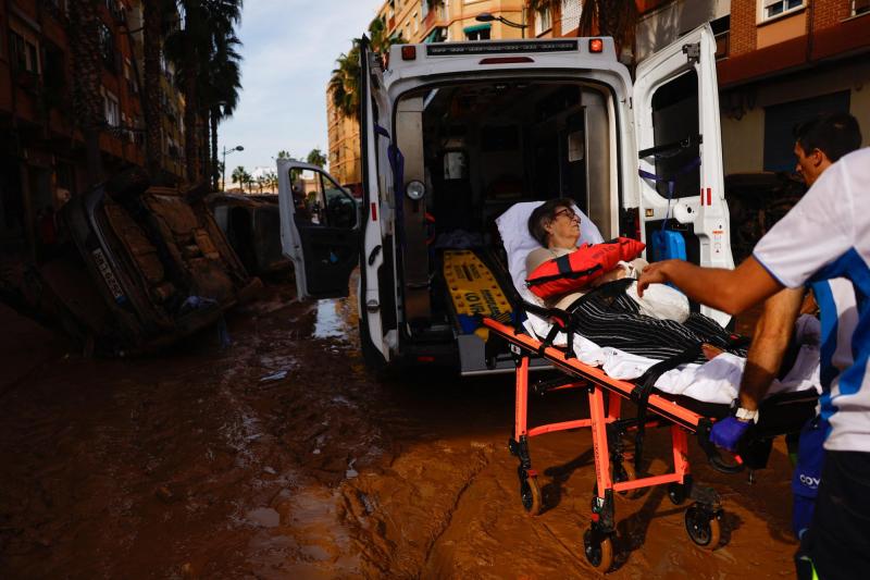 Una mujer es trasladada a una ambulancia por miembros de un servicio de emergencias, tras las fuertes lluvias caídas en España  - Reuters