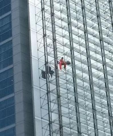Bomberos trabaja en rescatar a persona trepada en lo alto de un edificio en Apoquindo