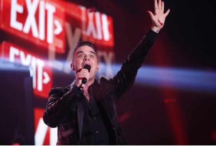 Robbie Williams se limpia las manos después de saludar a los fans