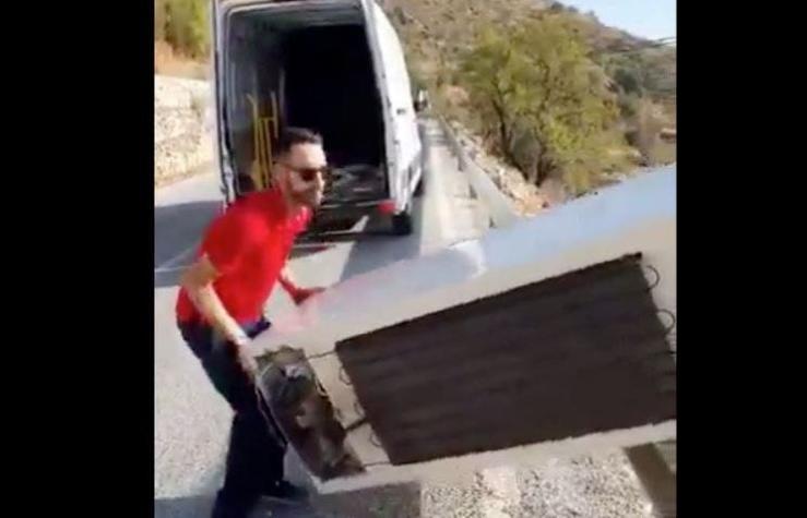 [VIDEO] Lanza un refrigerador por un barranco... y la policía lo castiga obligándolo a subirlo