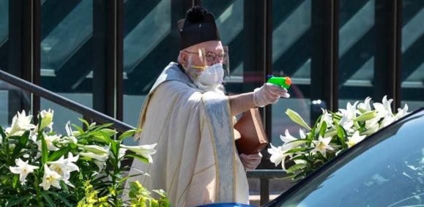 [FOTOS] COVID-19: Sacerdote apunta a sus fieles con pistola de juguete para darles agua bendita