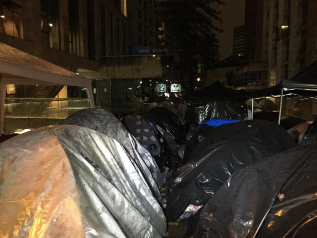 Ciudadanos colombianos permanecen frente al consulado de su país pese a la lluvia