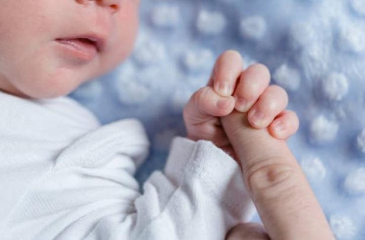 Recién nacido es fotografiado con dispositivo intrauterino de su madre en la mano