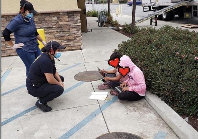 Dos niñas se sientan afuera de un local de comida rápida para usar el Wifi gratis y hacer sus tareas