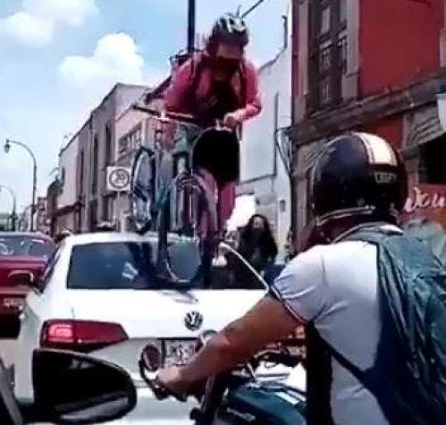 Ciclista pasa por arriba de un auto estacionado en un ciclovía en México