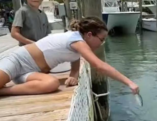 Una niña estaba alimentando a los peces: saltó uno del agua y casi le come el brazo